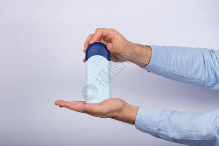 男人在白色背景上拿着一瓶洗发水或调味剂复背景图片