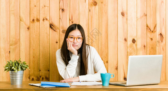 年轻女人在书桌上学习她无聊疲劳图片