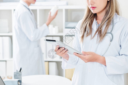 在数字平板电脑屏幕上读取信息的严重年轻女医图片
