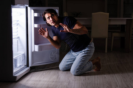 那个男人晚上在冰箱附背景图片