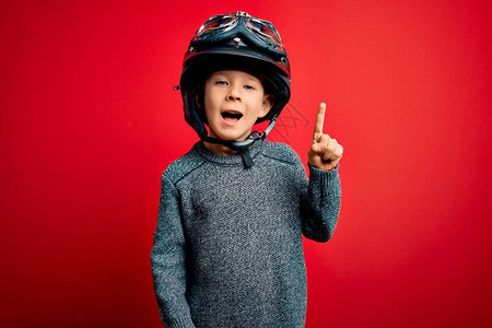 年轻的caucasian小孩穿着老式摩托车头盔和红背景的谷歌背景图片
