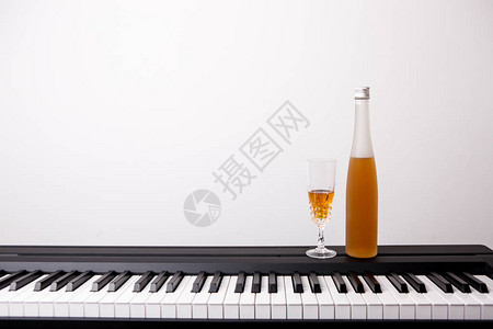 白色背景钢琴上的酒杯图片