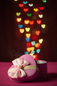 手拿礼物盒粉红礼物盒打开心形的心脏背景