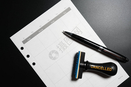 取消计划约会日程安排会议概念用空白日历钢笔和黑色背景上的橡皮图章取图片