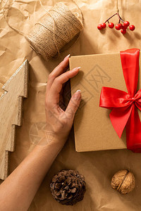 女手拿着工艺纸背景上的礼品盒带有圣诞气氛的冬季节日作文图片