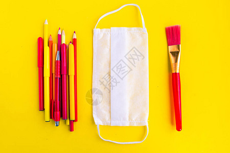 黄色背景上的彩色铅笔和医用口罩图片