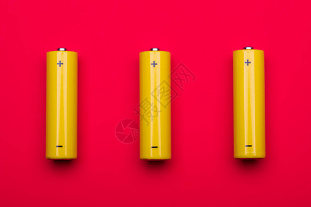 红色背景的3个黄色AA碱电池或可再充电的NiMH电池图片