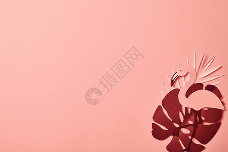 在粉红色背景的棕榈叶上剪纸火烈鸟的顶部视图背景图片