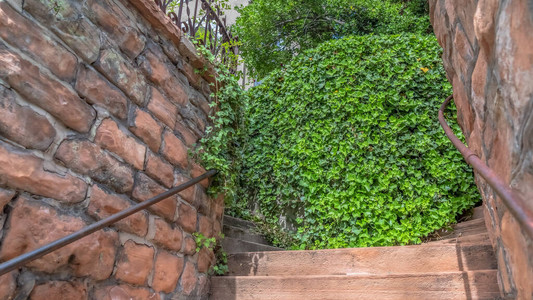 全景关闭通往家的石砖挡土墙中的室外楼梯楼梯周围还可以看到生锈的扶手锋利的护栏和郁葱图片