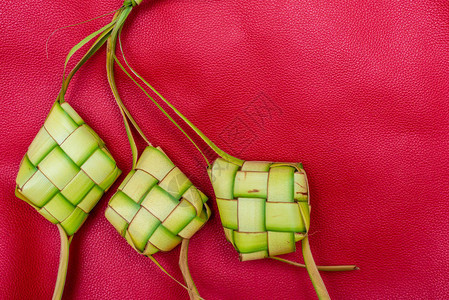 KetupatPouches以红色背景Ketopat是用包装在钻石形状的棕榈叶袋容器中的大米背景图片