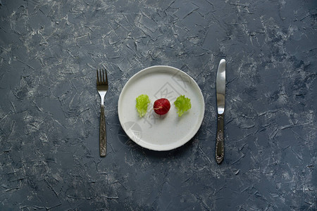 一个成熟的萝卜菜园沙拉叶白板在灰色表面叉子和背景图片