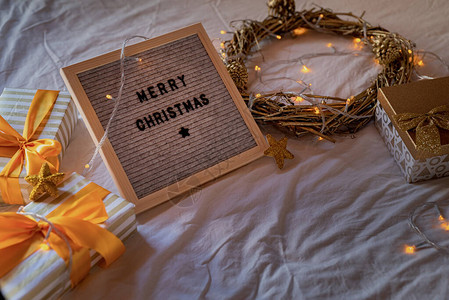 圣诞和新年概念在床上用金花圈灯光和礼品盒装饰的首字母板图片