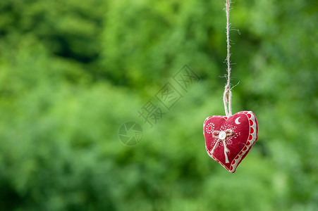 孤立的手工棉织物心挂在绿草背景的韧皮绳上挂在晾衣绳上的红色织物心夏季婚礼主题爱和图片