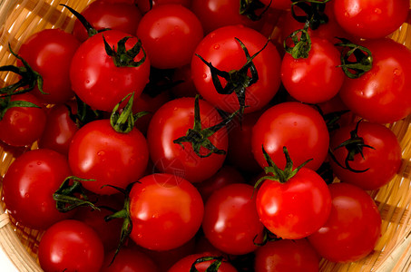 白色背景竹滤锅中的新鲜红樱桃番茄图片