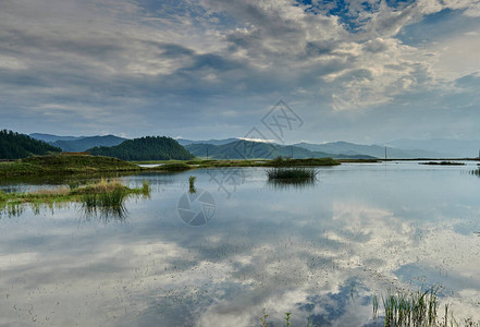 有天空反射的湖和被群山环绕的芦苇阿尔泰图片