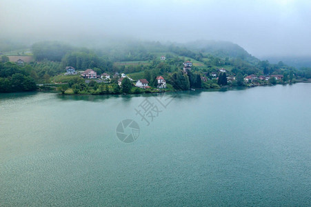 在寒冷的夏日早晨雾在山上向湖面蔓延图片