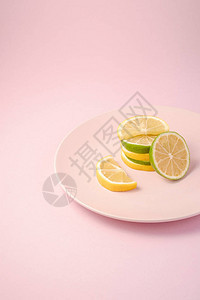 粉红色盘子上堆叠的鲜新美味的柠檬和柠檬柑橘水果切片图片