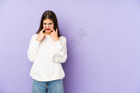 年轻caucasian女子被孤立在紫色背景下哭泣图片