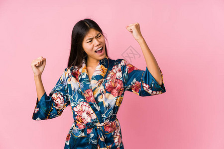 年轻的亚洲女人穿着和服睡衣在胜利后举拳图片