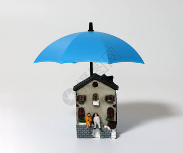 一对微型老夫妇坐在一把蓝色的雨伞和一座微型房子上图片