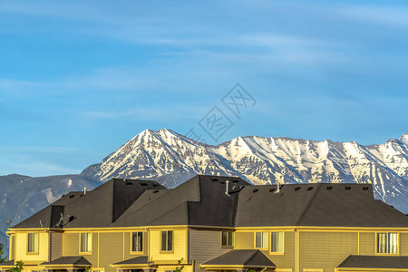 有水平墙的房屋顶着雪峰和蓝天在房屋的黑暗屋顶上可图片