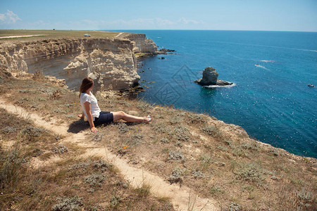 女孩坐在悬崖边缘蓝色的海边图片