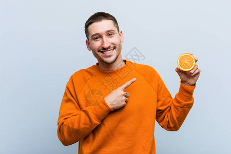 年轻caucasian男子拿着橙色的笑容图片素材