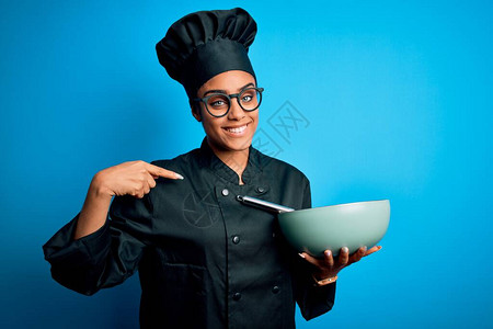 身着烹饪制服和帽子的年轻非洲女厨师女孩使用胡须和碗盘图片
