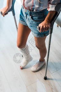 在诊所站着时持有拐杖的骨折妇图片