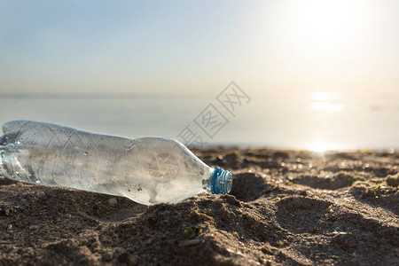 废弃塑料瓶装在沙海滨滩上漂流近水图片