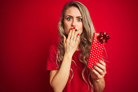 年轻漂亮的女人拿着情人节礼物盖在红色孤立的背景上图片