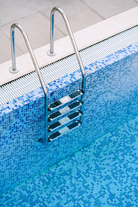 紧贴在泳池的楼梯上以蓝色马赛背景图片