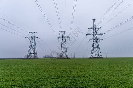 多云的天空和绿色的草地上的塔架电网背景图片