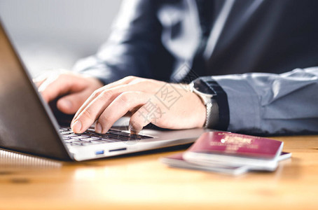 有护照和膝上型计算机的人旅行证件和身份证明移民书写电子公民申请申请数字签证在线机背景图片