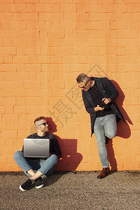 坐在地面交叉腿上和在笔记本电脑上工作的年轻caucasian男子图片
