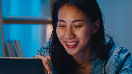 亚洲自由职业聪明的女商人晚上在家客厅里用笔记本电脑工作时吃方便面图片