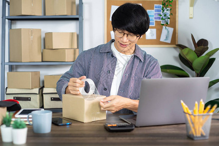 亚洲商人SME企业家或在纸板箱中工作的自由职业者为客户准备送货箱在线销售电子商务包背景图片