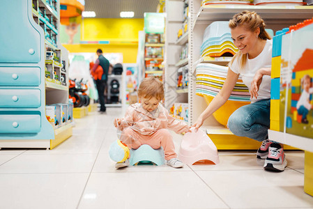 母亲和她的小女孩在儿童商店中选择婴儿便壶妈和孩子一起在超图片