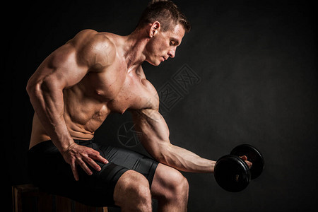 健身房运动和健康生活方式概念的健身英俊的健壮男子在深色背景上展示他训练有素的身体健美男模特用哑背景图片