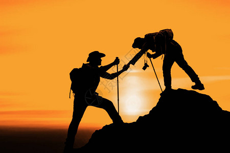 夏天日落背景的朋友帮助朋友爬山的剪影背景图片