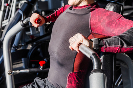 男子坐在长凳上抽肌肉的训练器械健身房照片胸部锻炼与重量他在健身中心图片