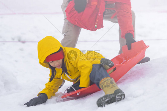 父亲正在帮助她的女儿骑雪橇图片