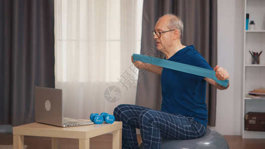 有活力的老人用阻力带观看在线节目进行健身锻炼图片