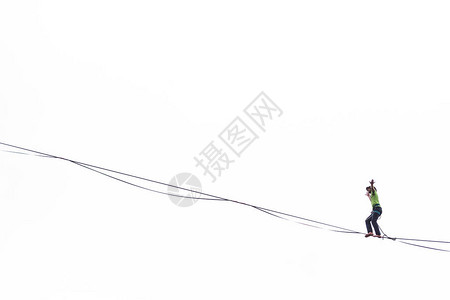 在白色背景上的Highliner反对天空的高线一名男子用拉长的吊索保持平衡赤脚走钢丝的人沿着这条线走平衡背景图片