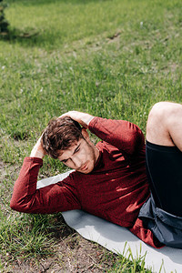 英俊运动员在公园健身垫上做腹肌图片