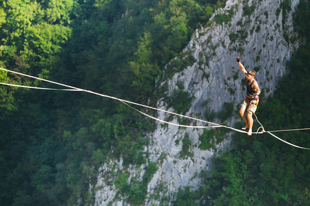 山中的高线一个人在伸展的吊索上前进Highliner上线了走钢丝的人保持平衡平衡对紧张背景图片