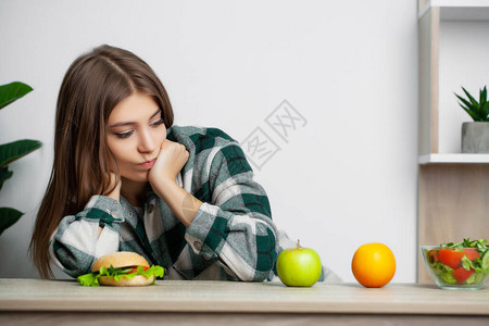 可爱的女人在健康食品和有害食品图片