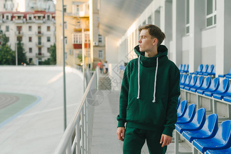 一名身穿绿色运动服的体育青年男子的肖像站在阳台附近图片