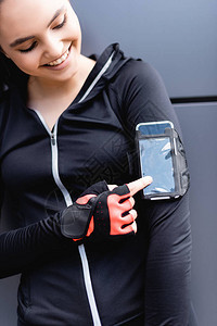 快乐女运动员用手指着手边机臂章中的智能手机图片