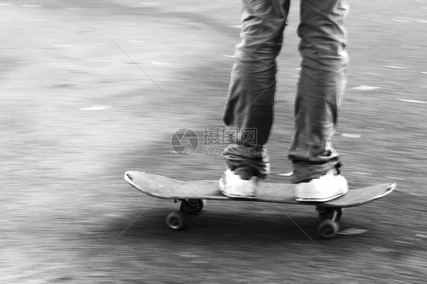 一个男孩在滑板上快速移动的细节黑白照图片